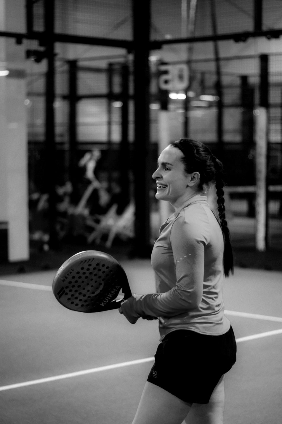 A smiling player holding her racket on an indoor court